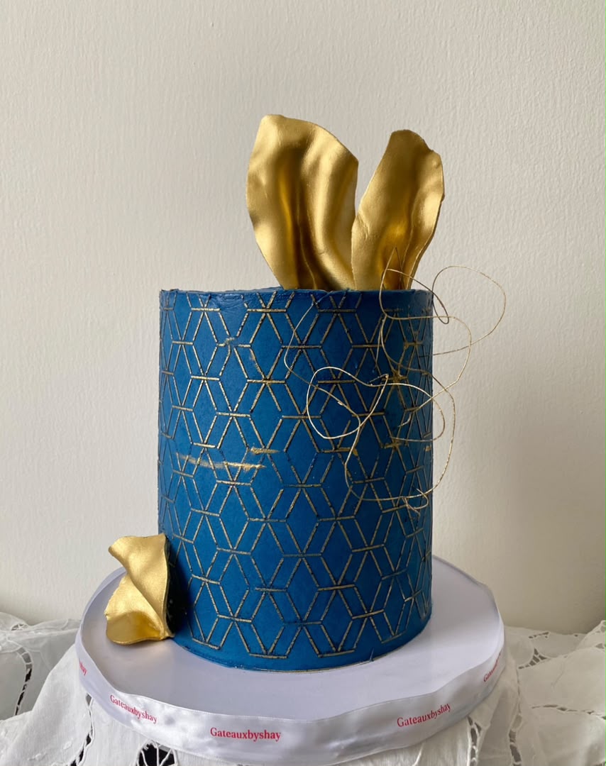 Navy blue cake with gold geometric pattern and gold sails