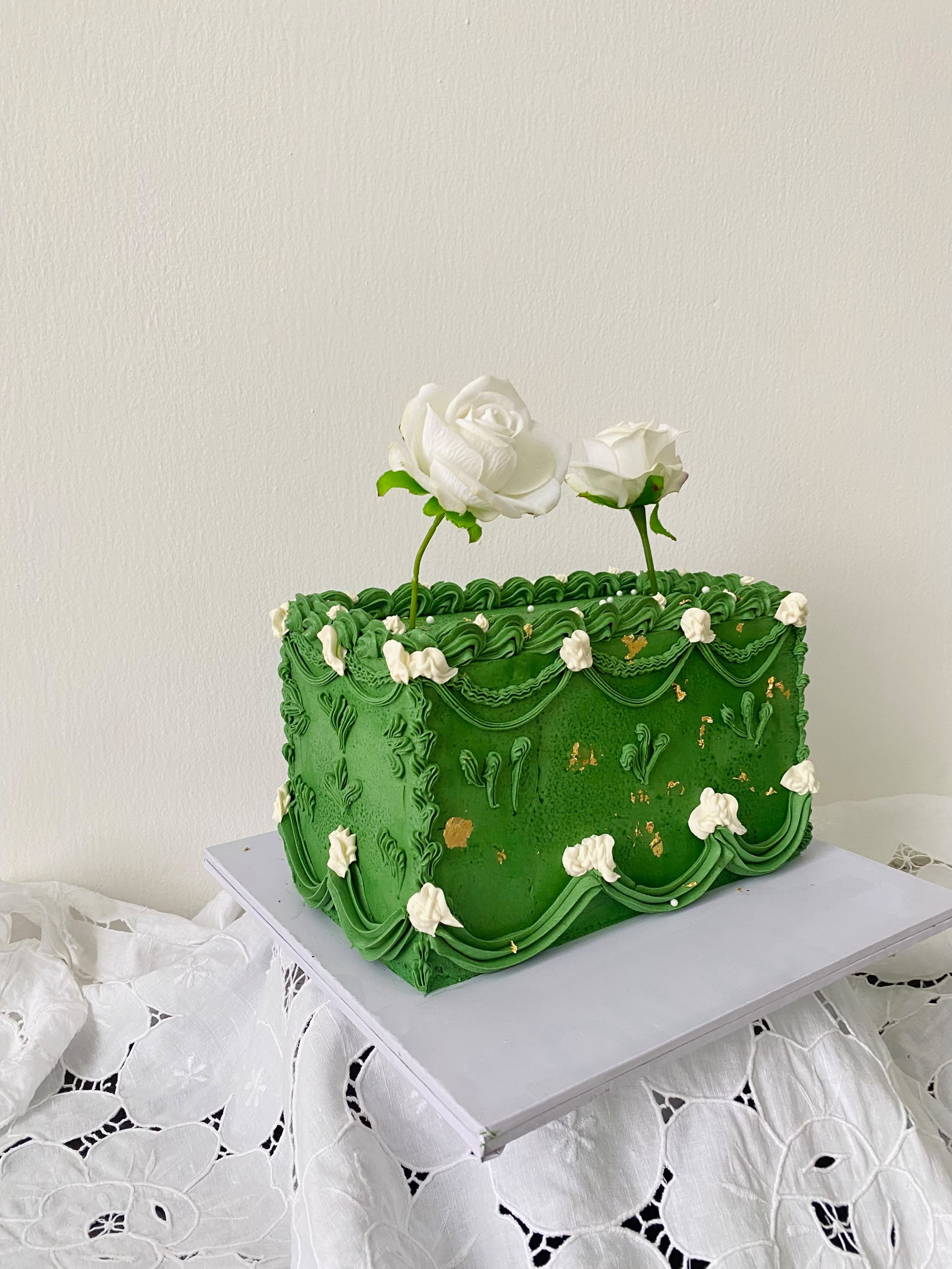 Green vintage piped cake decorated with white roses