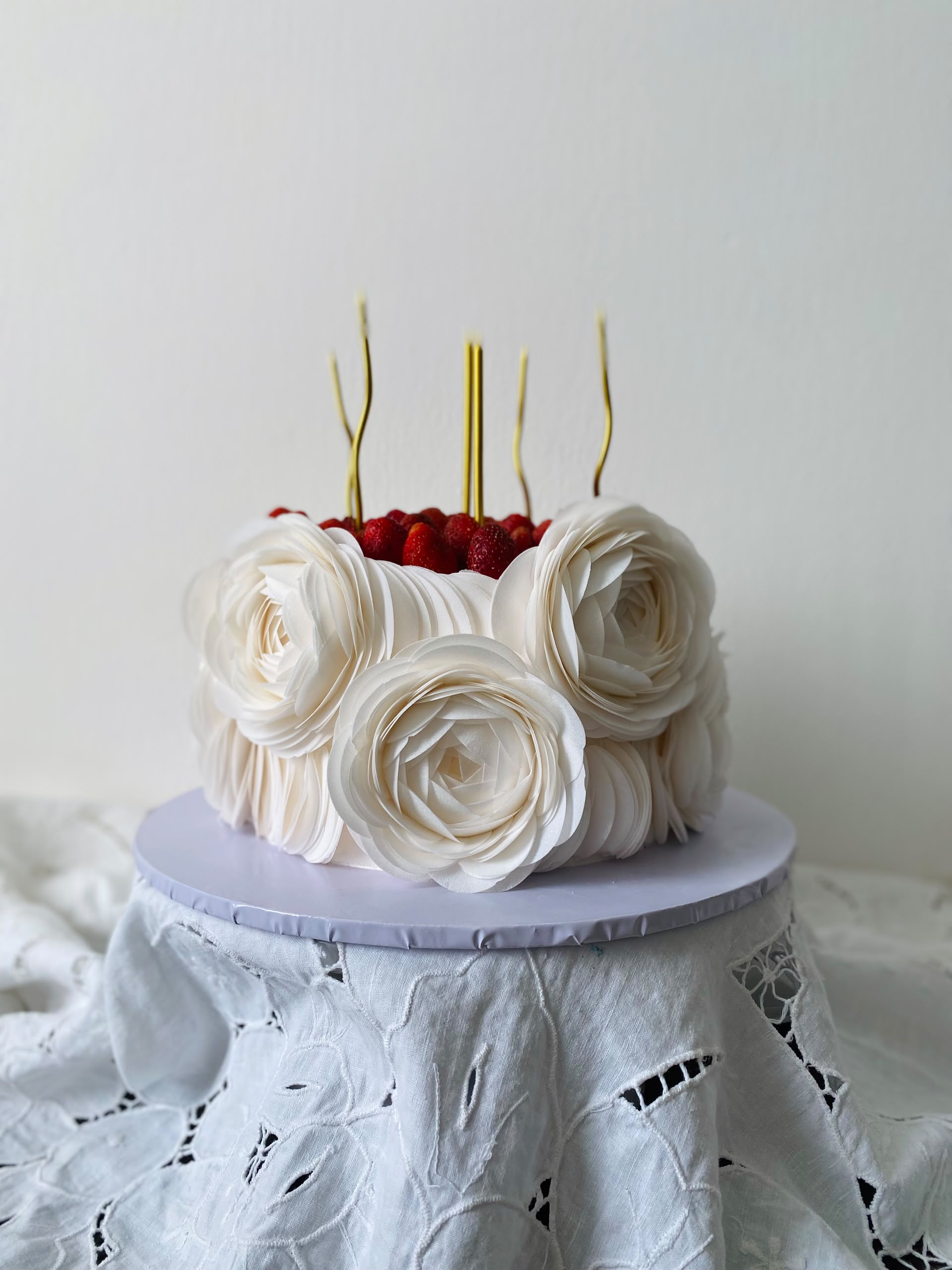 White ruffled rose cake topped with fresh strawberries